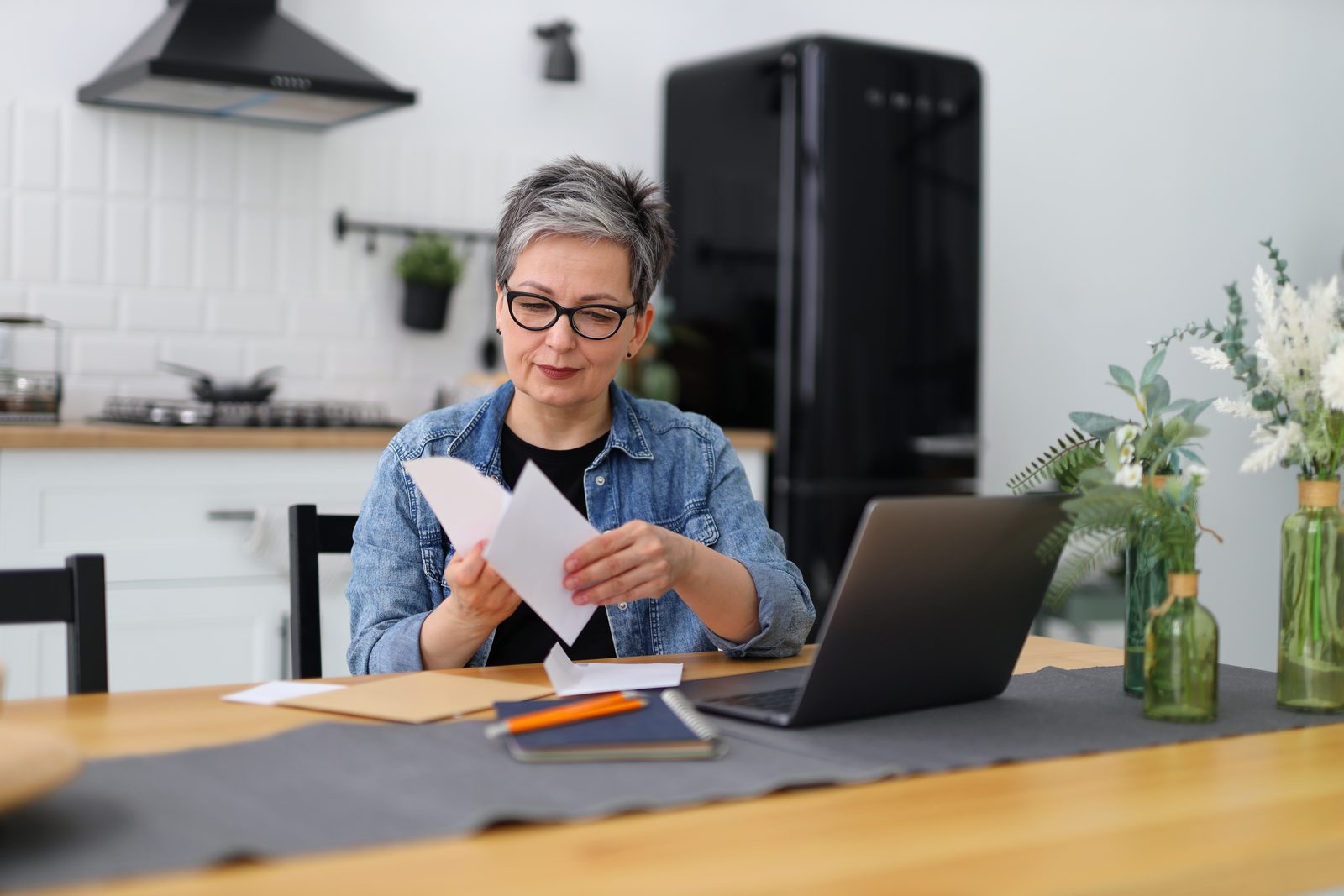Woman reviewing mail and bills at her kitchen table