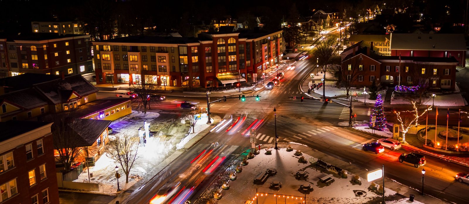 Aerial view of a small-town intersection at night with traffic light trails